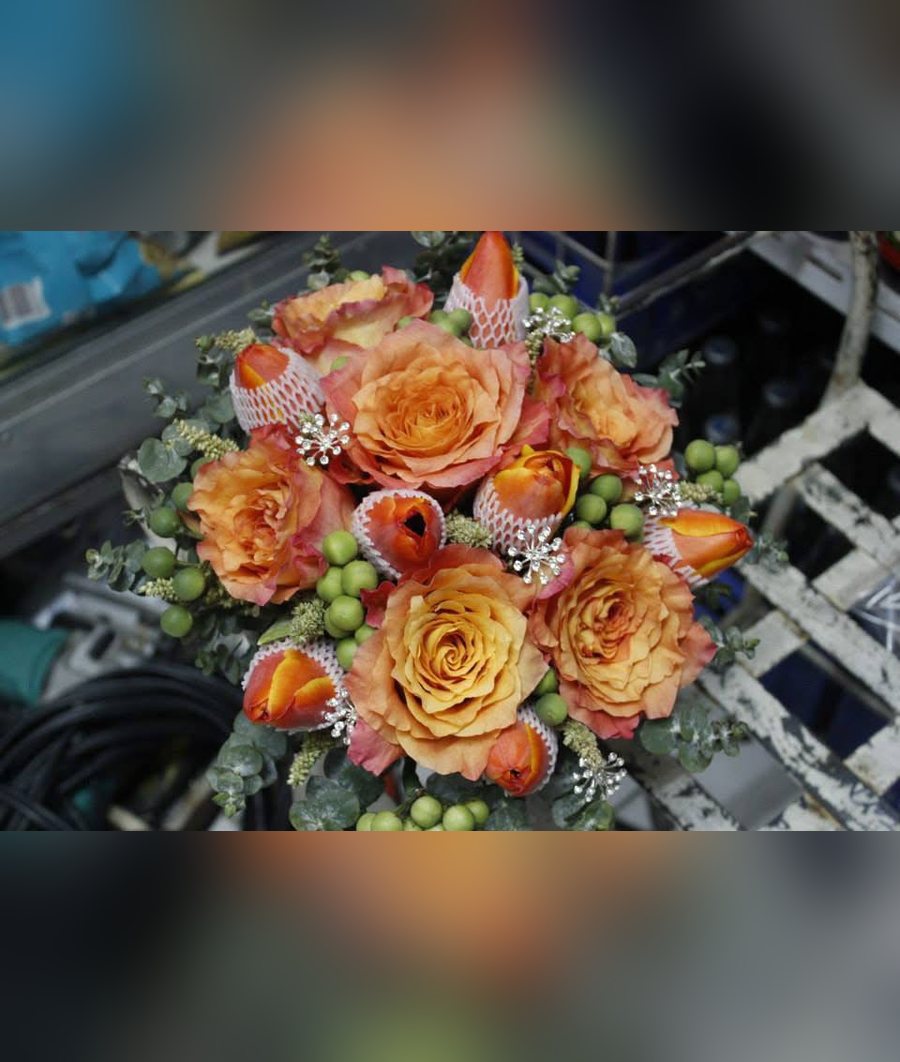 Orange rose and tulip bridal bouquet with green berries, eucalyptus and crystal accents
