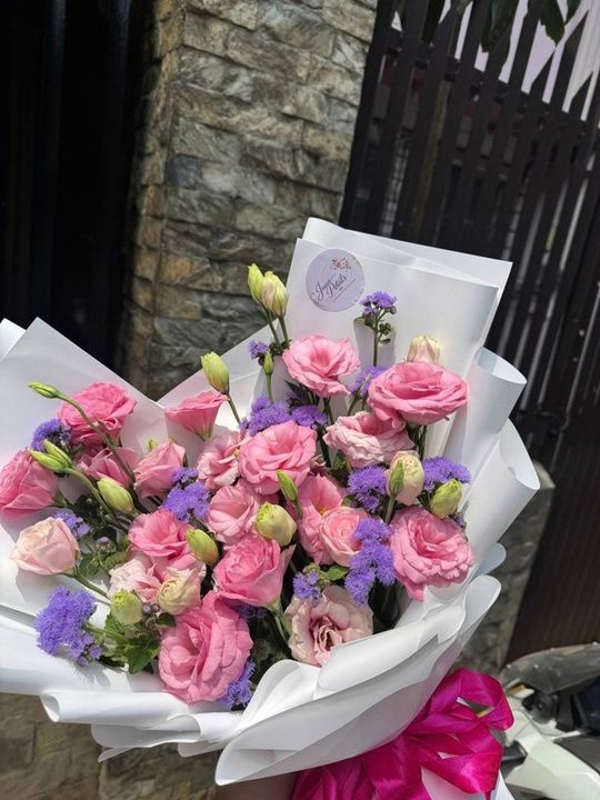 Lisianthus bouquet with purple filler flowers and white wrap