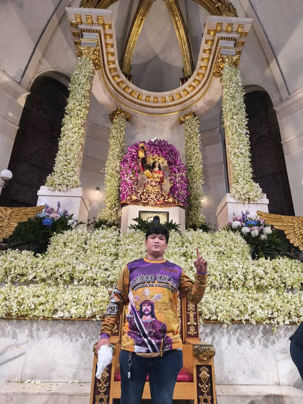 Kuya Zy, founder of Juan Petals PH, holding the shop sign among finished bouquets